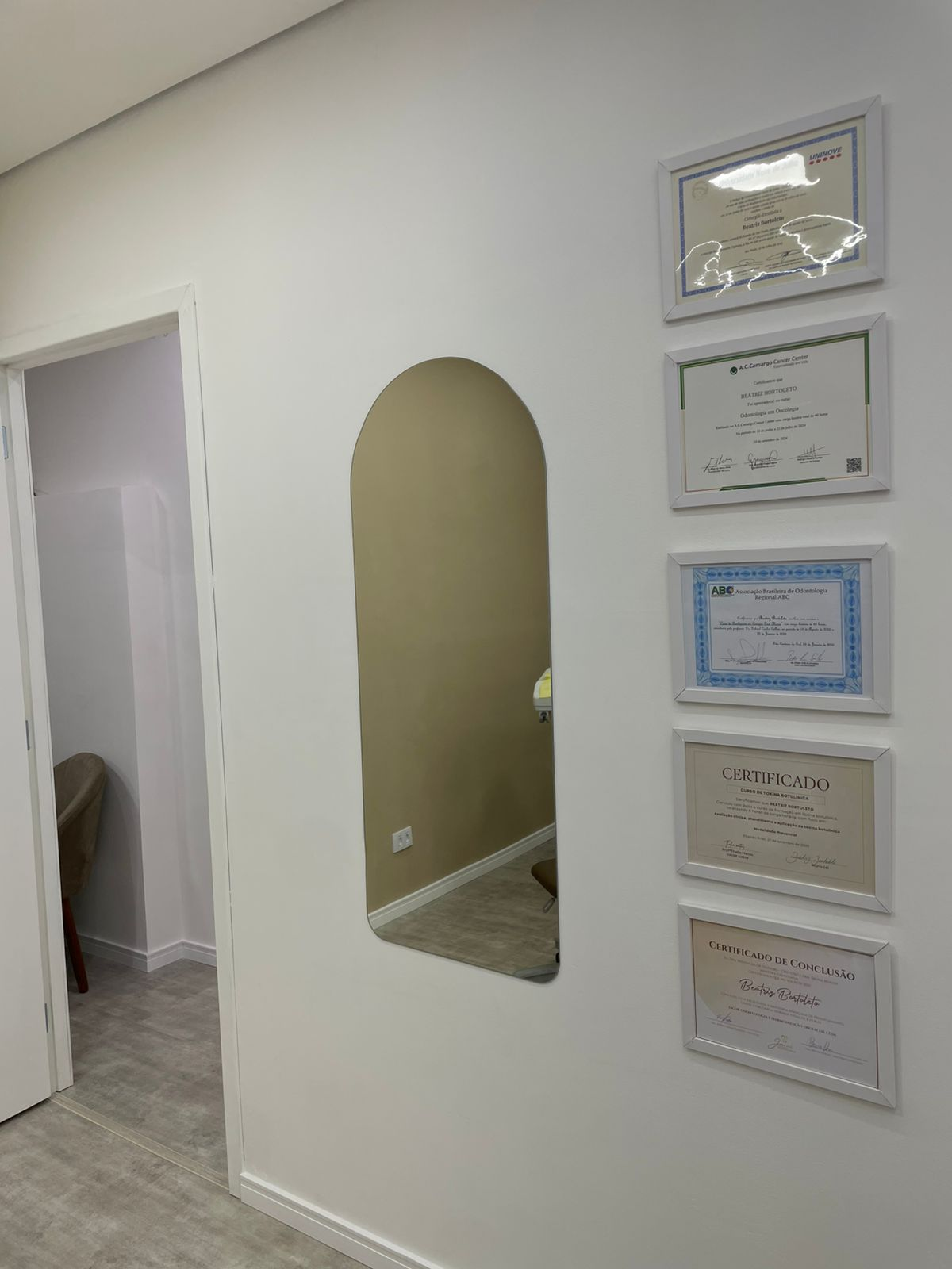 Corredor interno da clínica com certificados e espelho